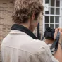 Leofoto L-CS-207 black camera strap worn around the neck of a photographer holding a DSLR, featuring a quick‑attach ball system and ergonomic comfort.